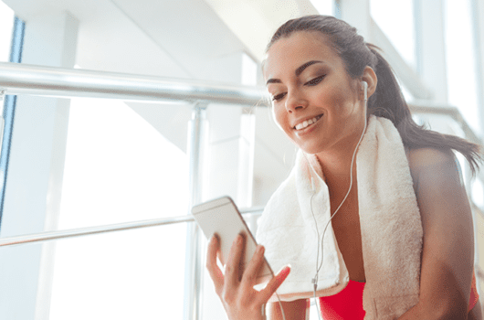 woman checks phone on the treadmill of a gym