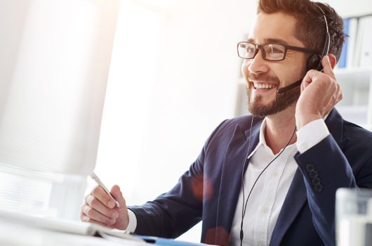 man looking at computer talking on headset