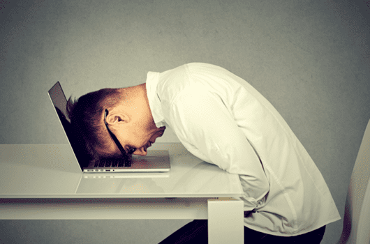 Person with head buried in the keyboard of a laptop.