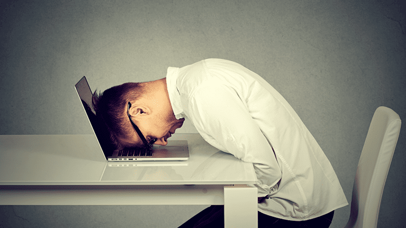 Person with head buried in the keyboard of a laptop.