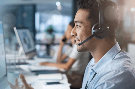 man with a headset talks in front of computer