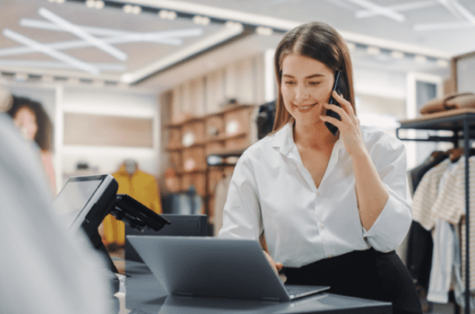 woman with a mobile phone talks in front of computer