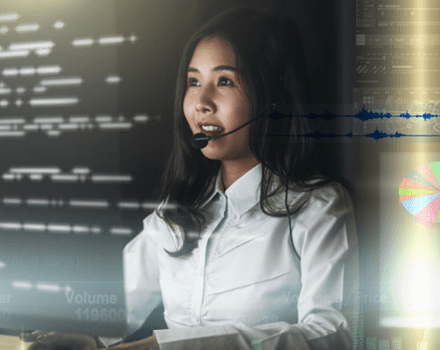 woman with headset sits in front of computer