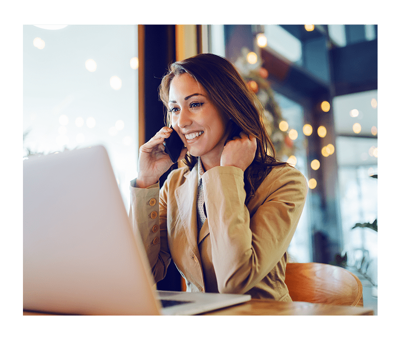 woman talking into mobile phone at computer